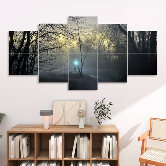 In a softly lit lounge, all ten panels hang above a low wooden console. The misty-forest image spans a warm white wall, drawing the eye to the glowing teal orb nestled among the trees. Below, a simple console holds neutral-toned decor, and a wicker chair sits at the left, framing the installation