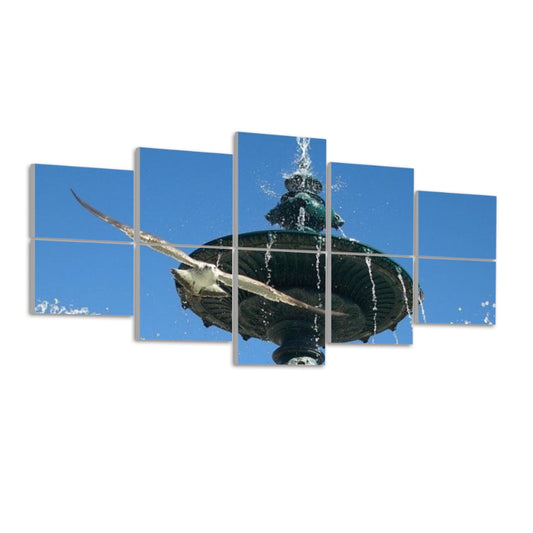 Side view of ten panels displaying the Lisbon fountain and seagull against a white background. The bright blue sky occupies the top panels, while bronze fountain details and water droplets appear below. A seagull’s wingspan crosses multiple panels