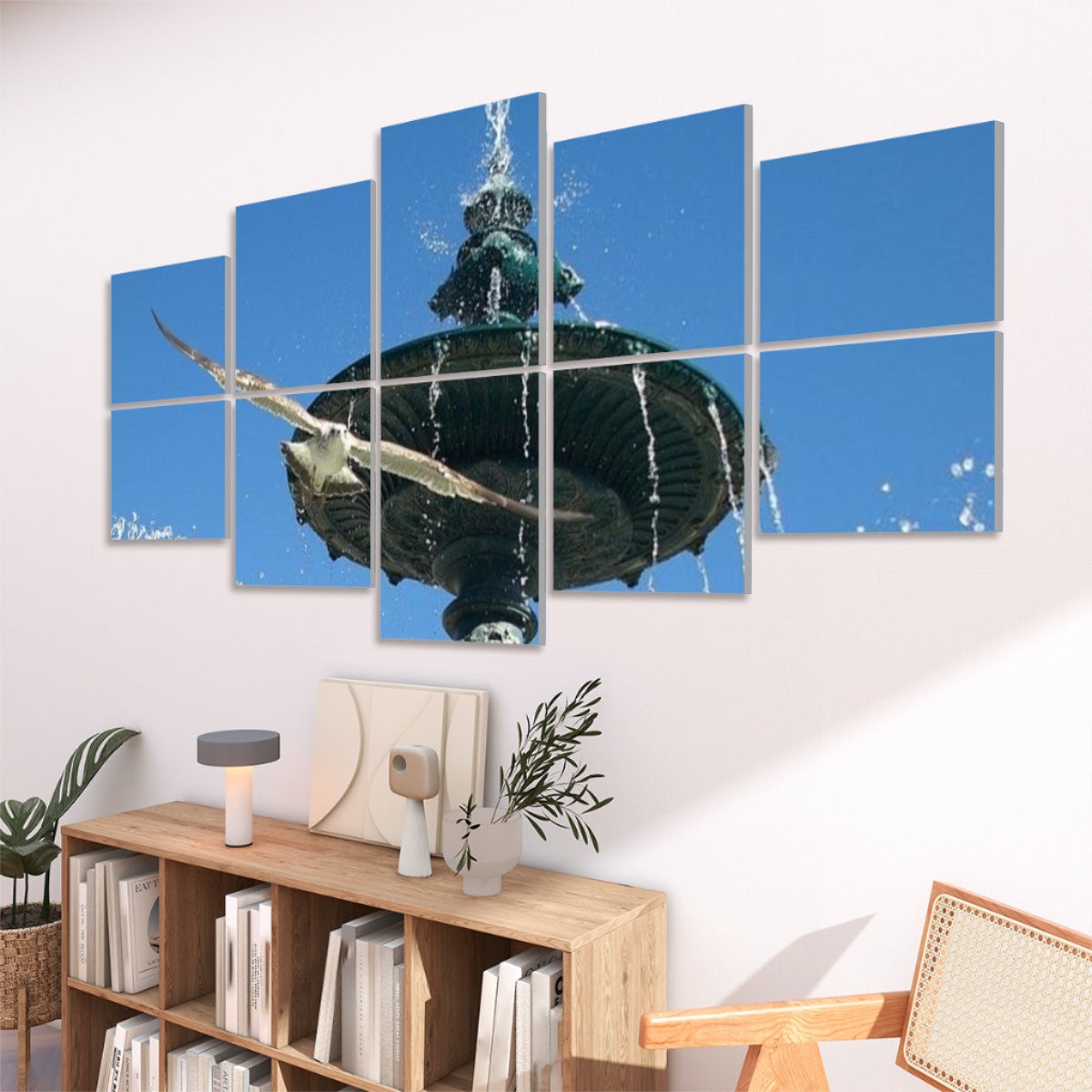 Side view of ten panels displaying the Lisbon fountain and seagull against a white background. The bright blue sky occupies the top panels, while bronze fountain details and water droplets appear below. A seagull’s wingspan crosses multiple panels