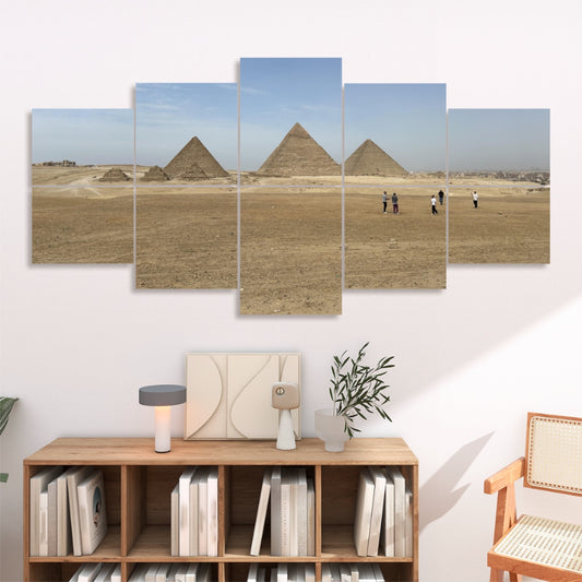 Desert landscape with the pyramids of Giza under a clear blue sky, with a few people walking in the distance