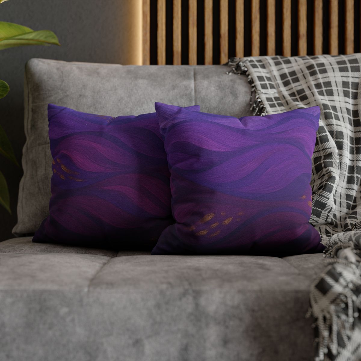 Two 14" × 14" Abstract Wave “Gilded Amethyst” pillowcases side by side on the corner of a gray sofa—one showing front, the other back