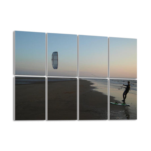 left angle. Kitesurfer on wet sand at sunset, holding lines with the kite above and the sky fading from blue to warm hues, spanning 8 decorative acoustic panels.