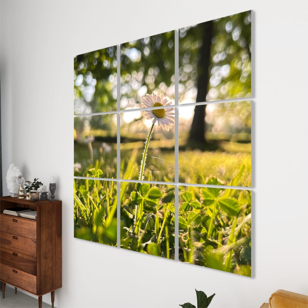 Right angle view of 9 sound absorbing panels showing a sunlit daisy and low-angle grass with blurred trees in the background.