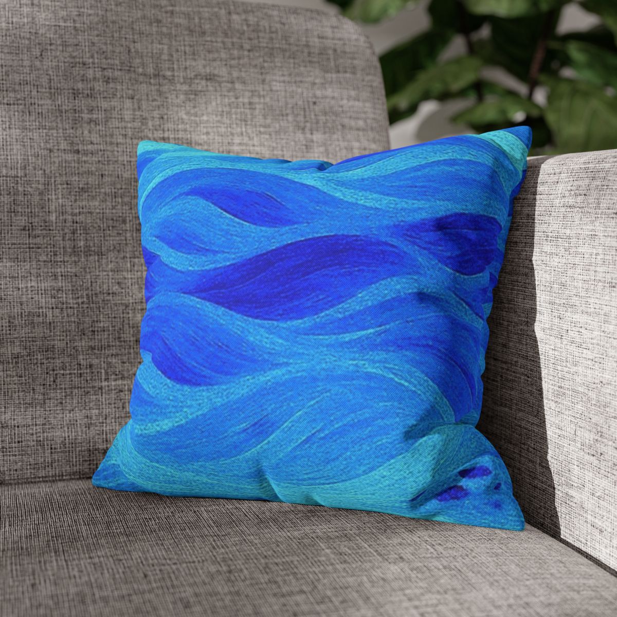 14" × 14" Abstract Wave pillowcase in Azure placed in the corner of a gray sofa