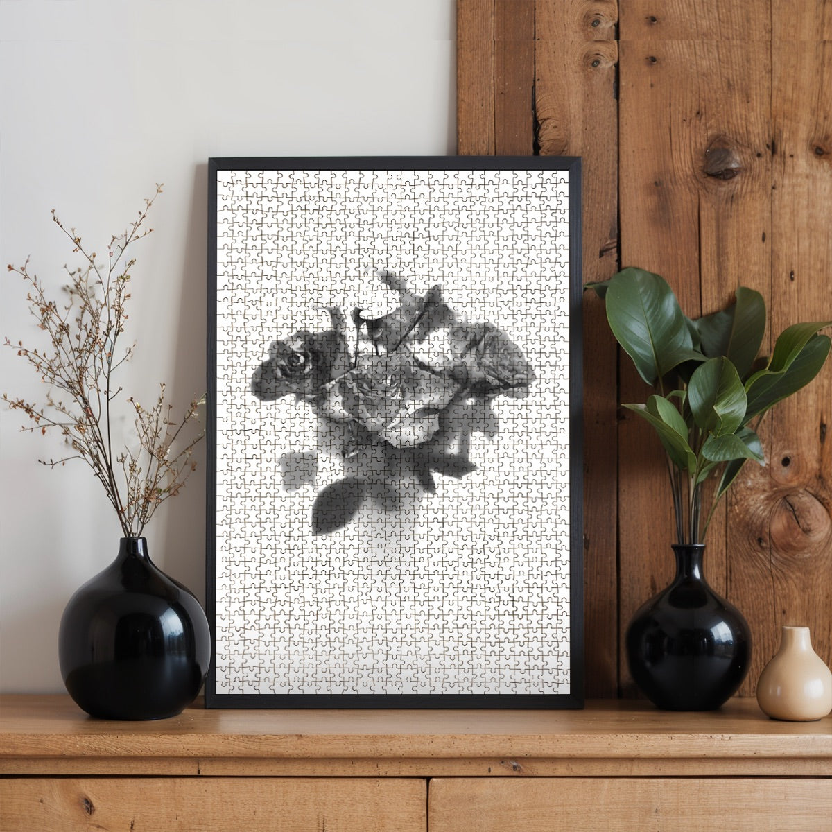 Living‑room mock‑up displaying the completed greyscale rose bouquet jigsaw puzzle framed above a sofa, illustrating finished size and monochrome elegance.