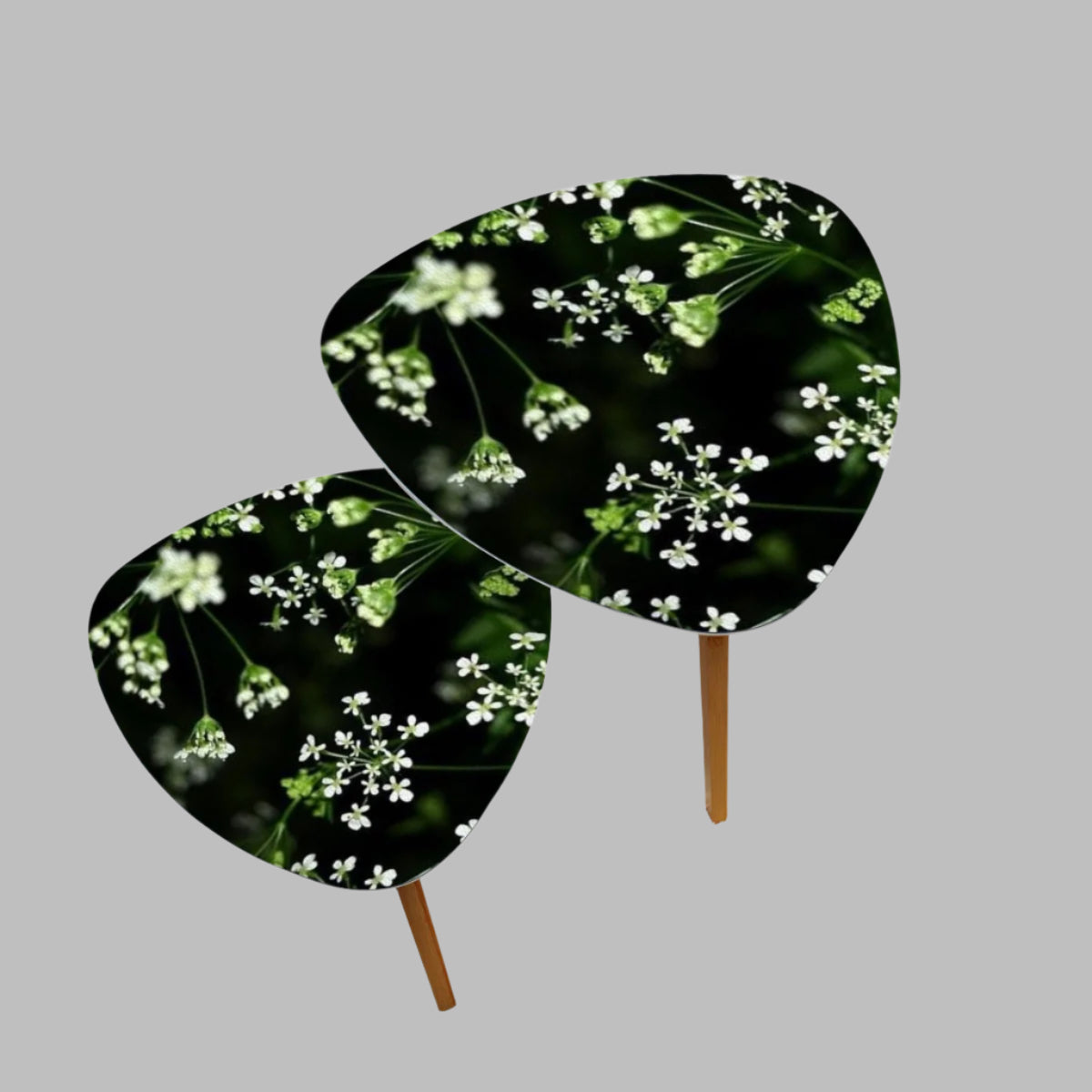 set of 2 floral triangular coffee tables featuring white little flowers on black background with green stems emerging from it