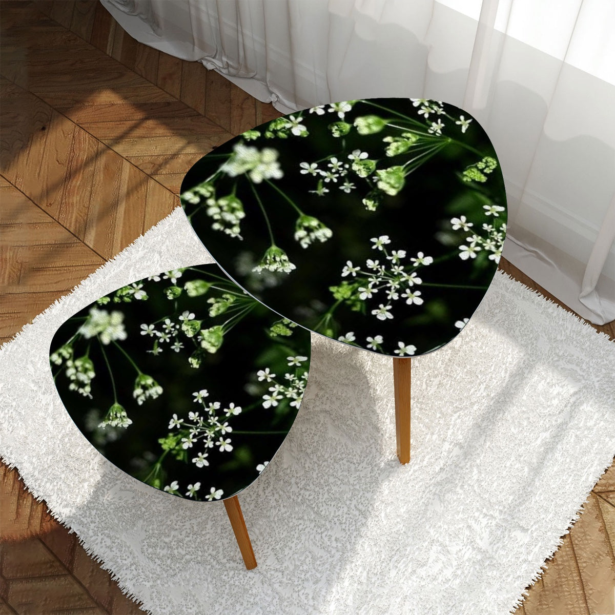 set of 2 floral triangular coffee tables featuring white little flowers on black background with green stems emerging from it
