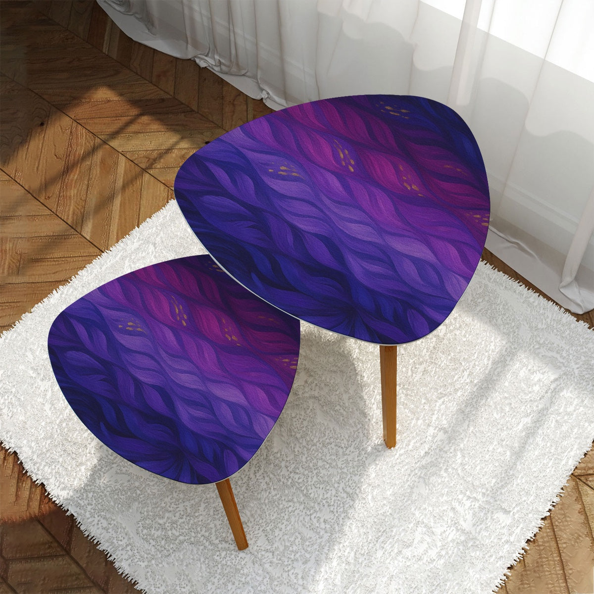 Pair of nested triangle tables with purple-gold leather tabletops arranged on a white rug in front of sheer curtains; bamboo legs rest on wood flooring