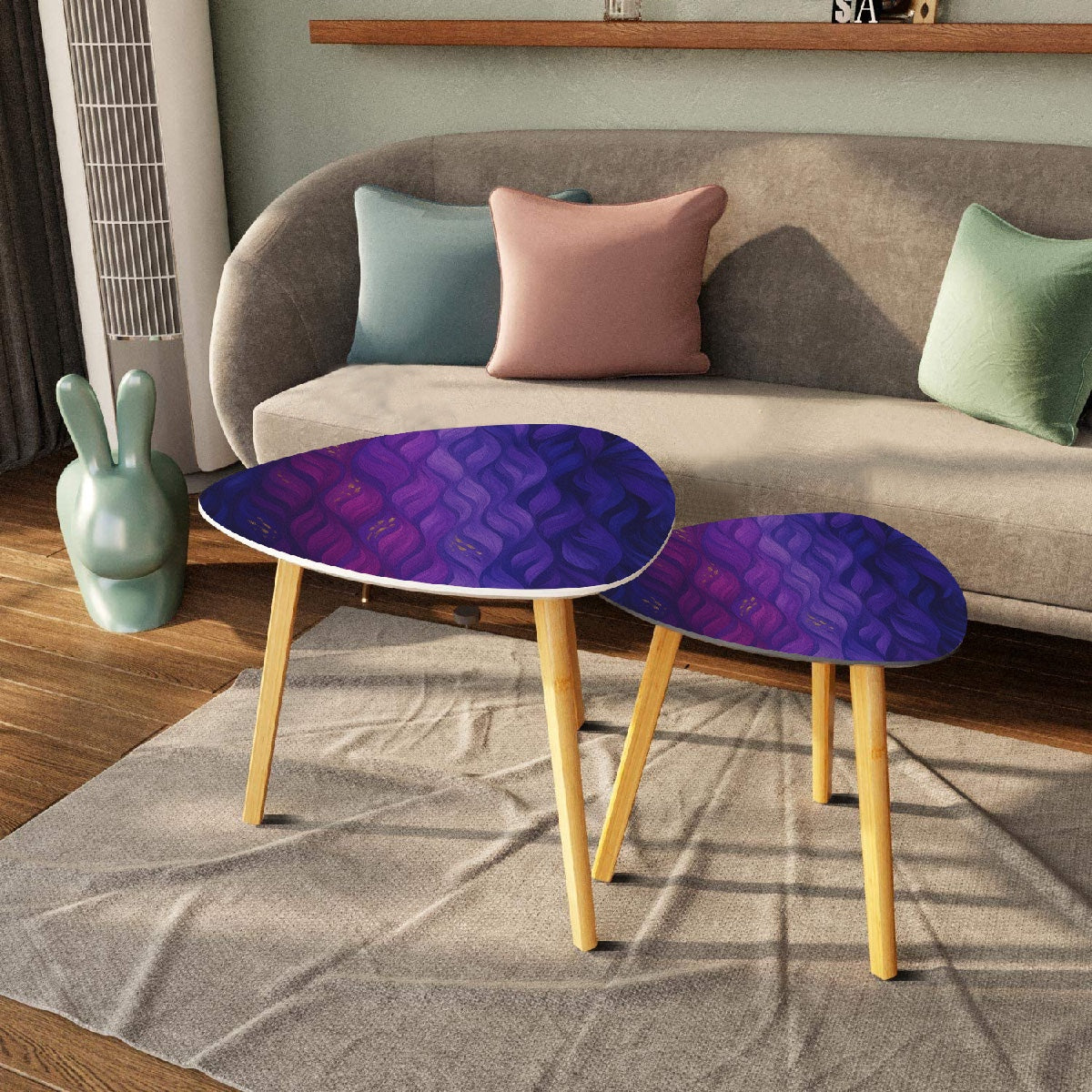 Pair of nested triangle tables with purple-gold leather tabletops arranged on a white rug in front of sheer curtains; bamboo legs rest on wood flooring