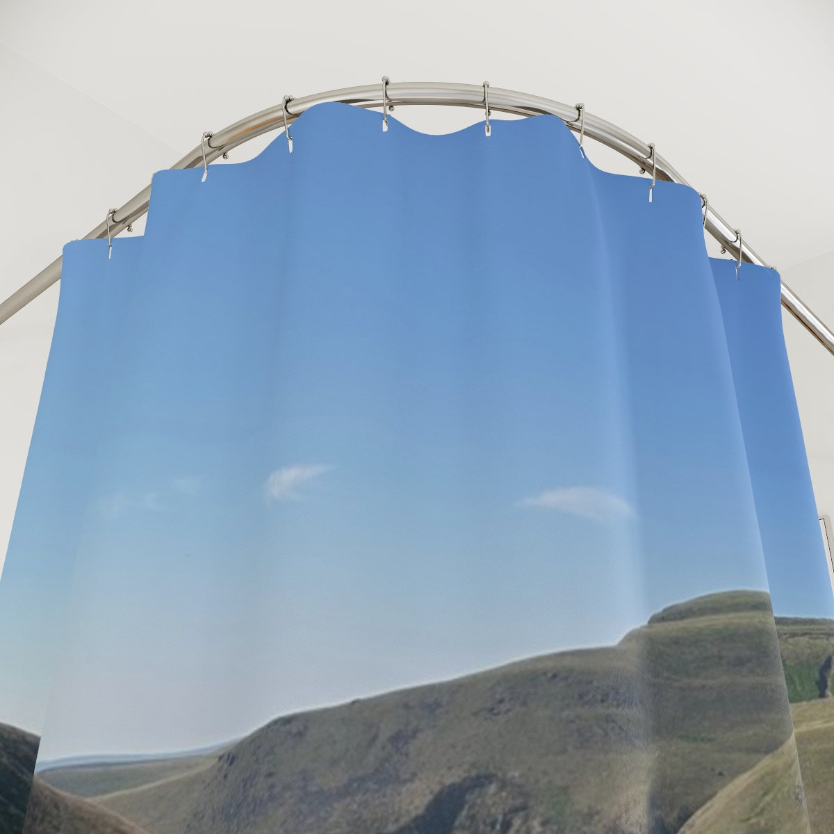 Close-up of curtain fabric revealing textured grass and hillside path under a clear blue sky