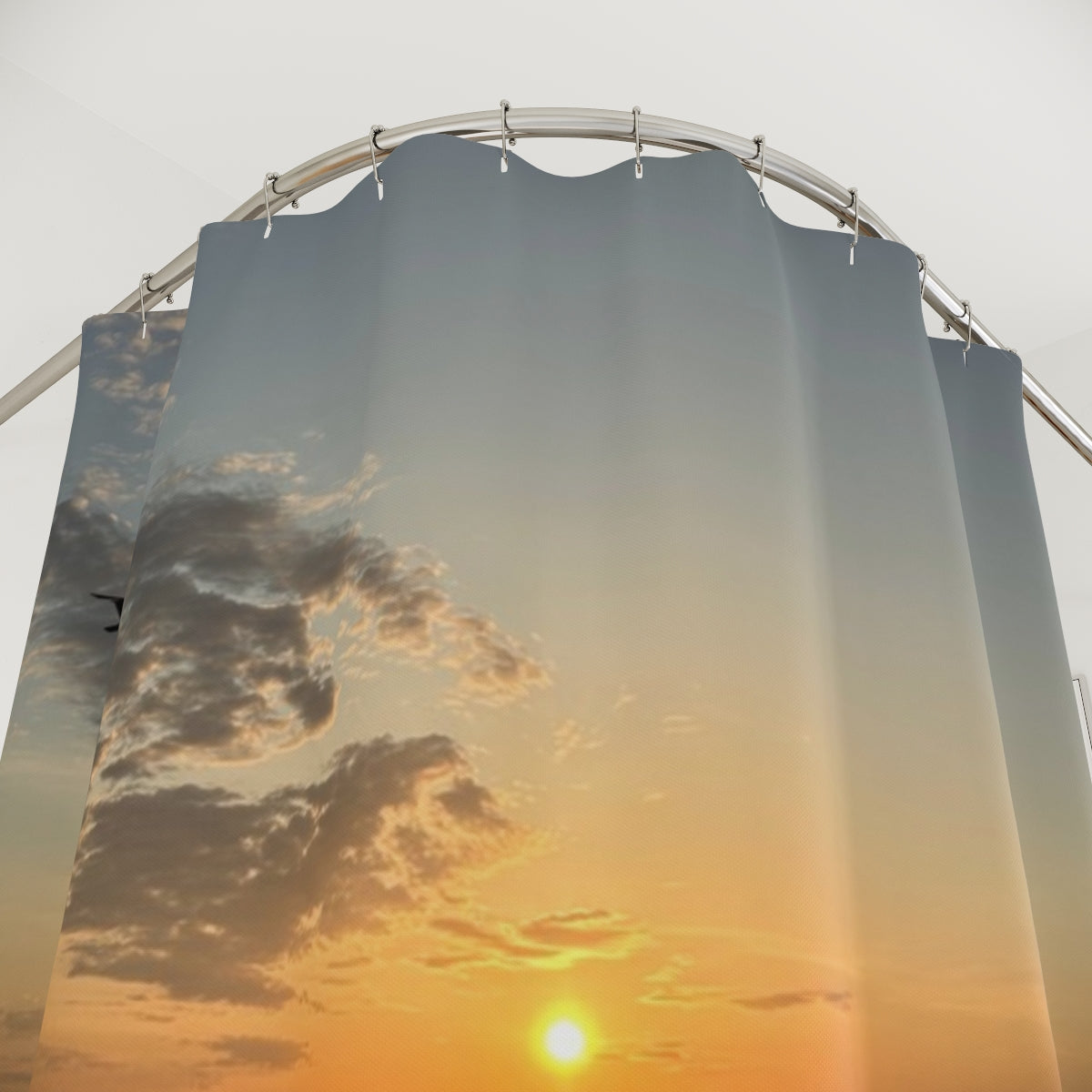 Close-up of curtain fabric displaying the sun setting behind scattered clouds above reflective tidal pools