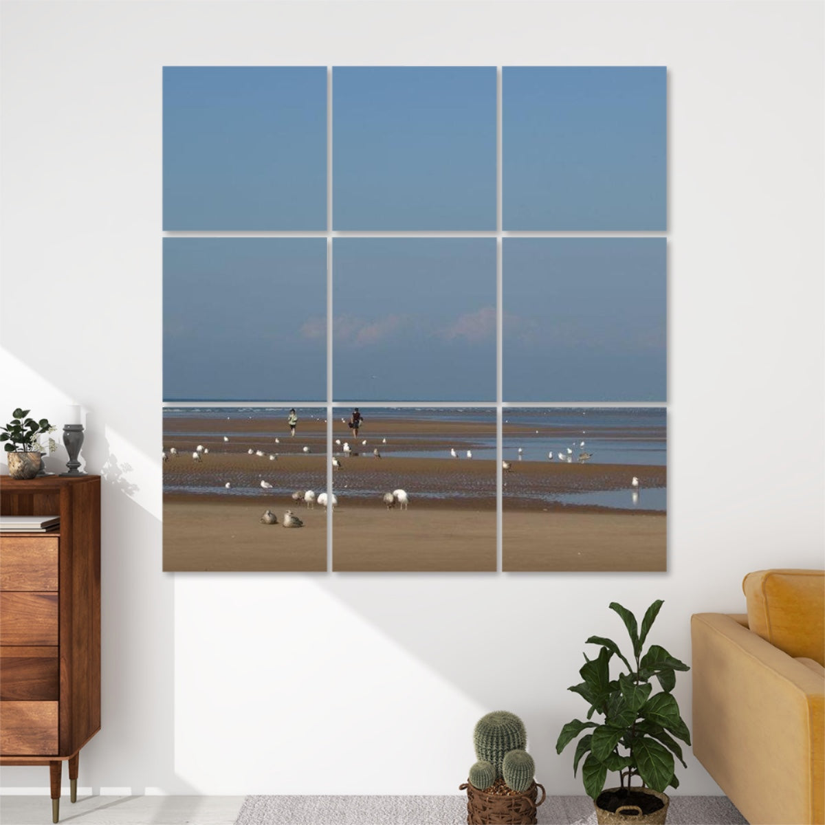 Front view of 9-panel acoustic wall art featuring a beach at low tide with scattered seagulls, two people walking, and a distant pier under a blue sky.