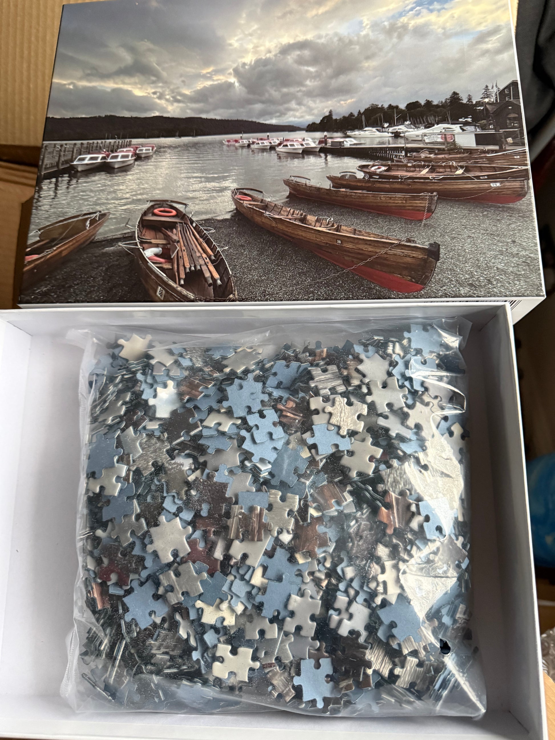 Puzzle box with a scenic image of boats on a lake and puzzle pieces inside.