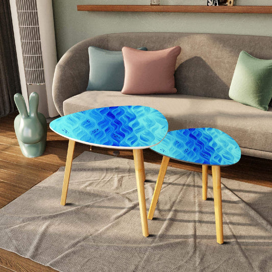 Two nested triangle tables featuring blue-teal leather tabletops, placed beside a gray sofa on a neutral rug; bamboo legs on hardwood floor