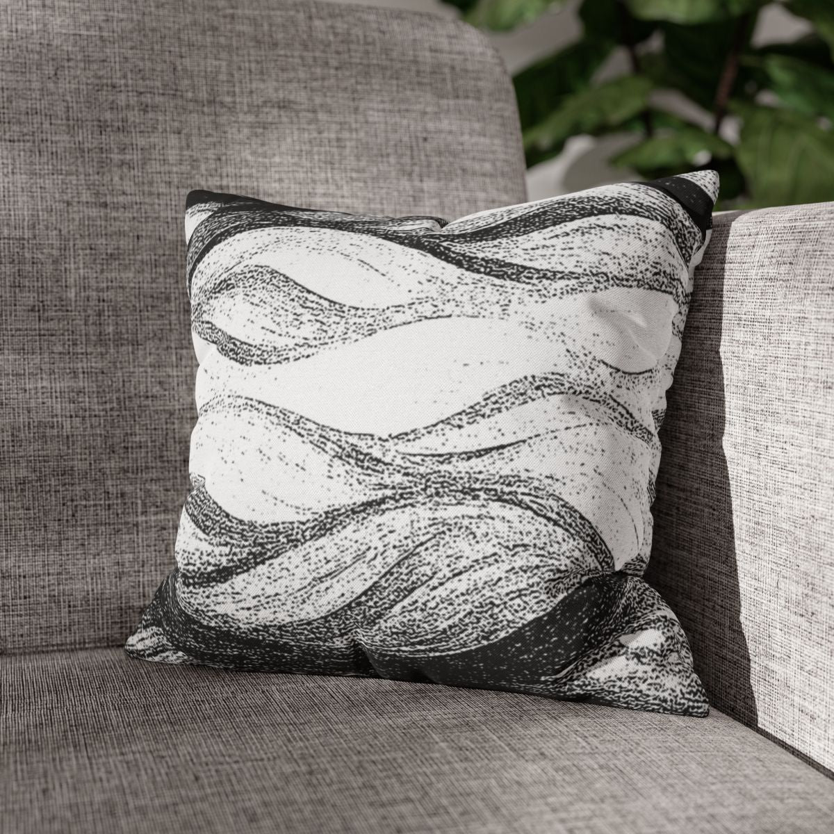 14" × 14" Abstract Wave pillowcase in Black & White placed in the corner of a gray sofa
