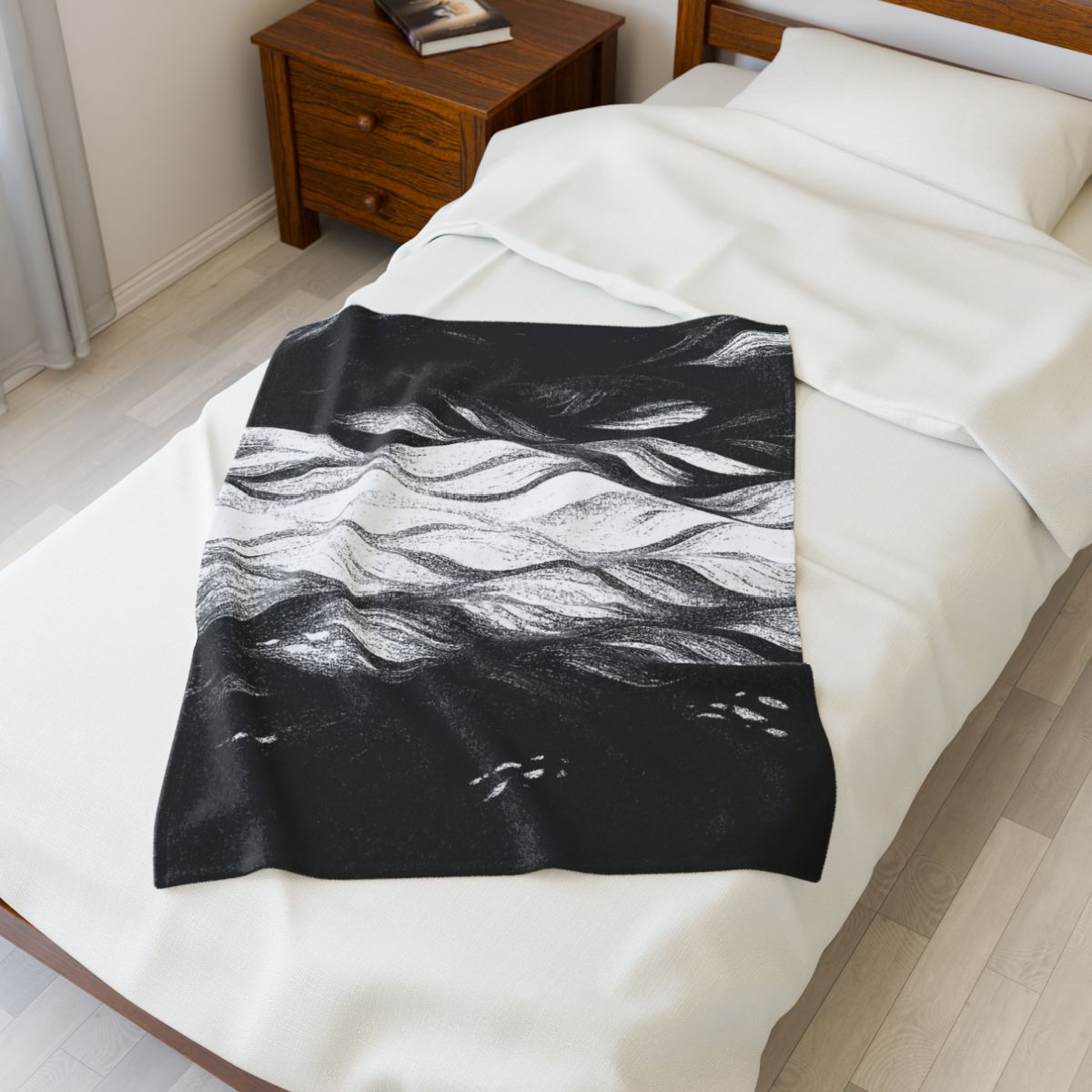 Black and white throw blanket with high contrast waves in charcoal and ivory, set on a single bed