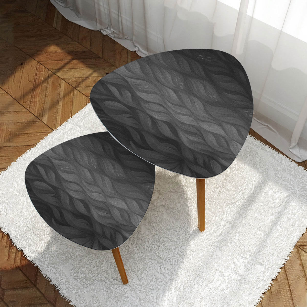 Two nested triangles with grayscale leather tabletops, positioned on a white shag rug before a pale gray sofa; bamboo legs beneath