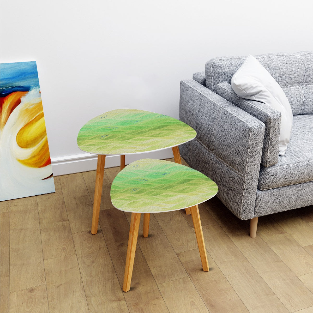 Nested triangle tables with chartreuse-lime leather tabletops beside a gray couch on light wood flooring; bamboo legs support each tabletop