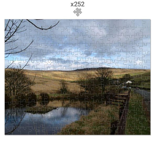 Jigsaw puzzle with a completed landscape scene featuring a river, trees, and sky.