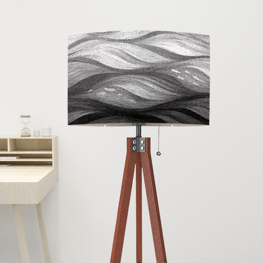 Tripod floor lamp with a linen shade showing bold black-and-white wave patterns, supported by a wooden tripod, casting crisp contrast against a neutral wall
